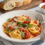 Plated Creamy Tortellini with Tomatoes Recipe garnished with basil and parmesan.