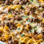 A perfectly baked sour cream beef noodle casserole with golden cheese topping, garnished with parsley.